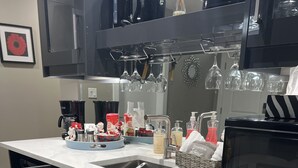 Una cocina con microondas, cafetera y copas de vino sobre la encimera.