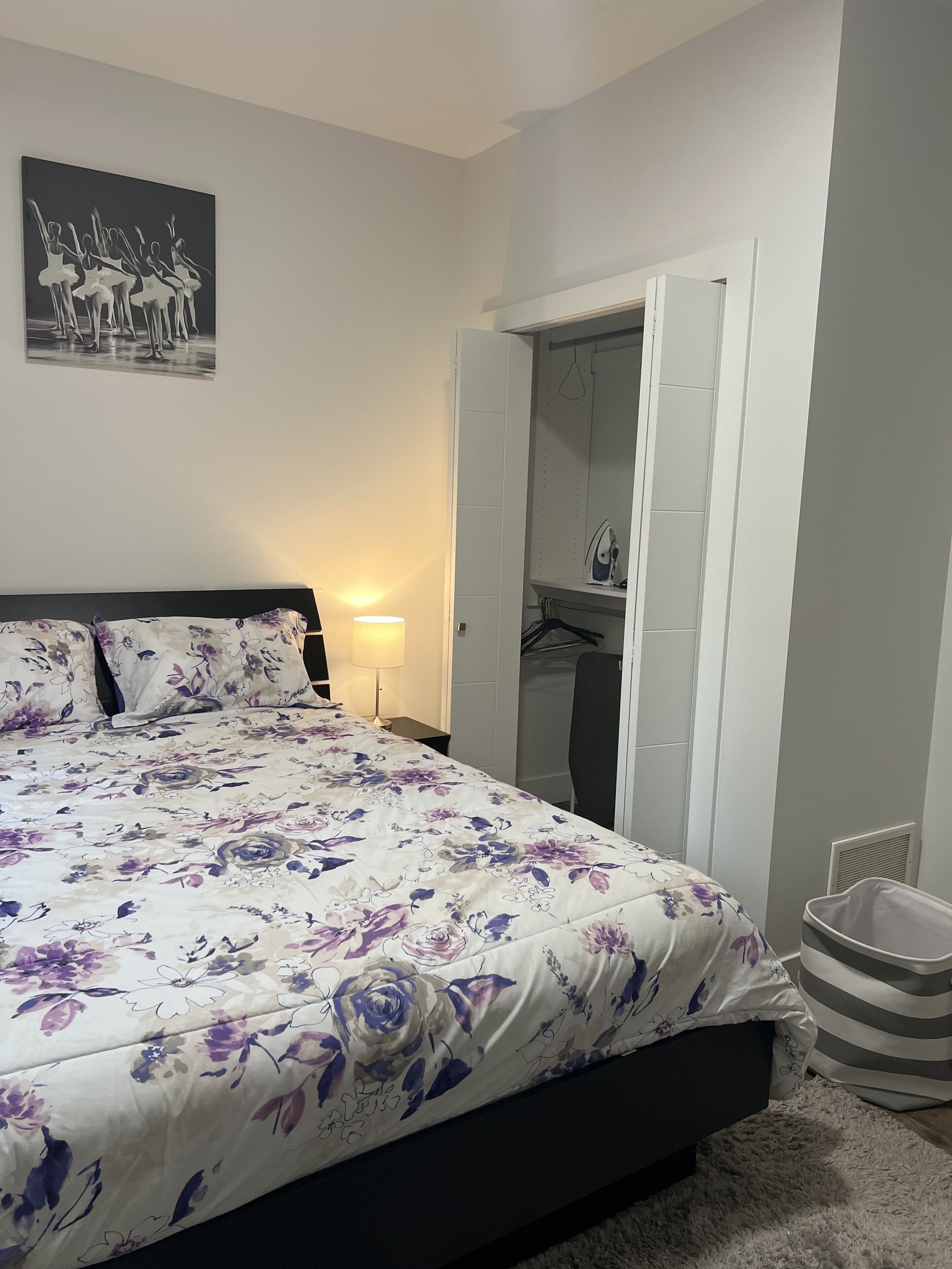 Bedroom with wardrobe including extra bedding, iron and table.