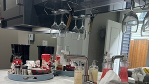 Una cocina moderna con un lavamanos integrado, una cafetera y diversos utensilios de cocina sobre la encimera.