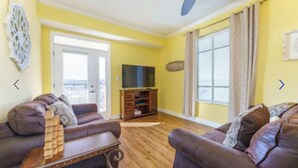 A living room with a brown leather sofa, a wooden coffee table, and a television on a stand.