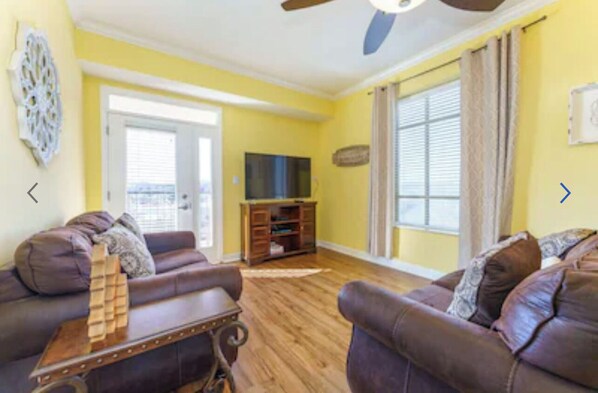 A living room with a brown leather sofa, a wooden coffee table, and a television on a stand. - Gorgeous 3 bed, 2 bath condo on the river! (Sevierville)
