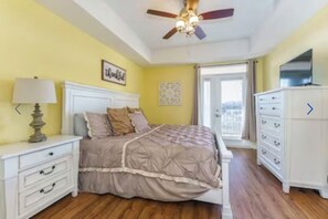 A bedroom with a bed, a nightstand, a dresser, a ceiling fan, and a window. - Gorgeous 3 bed, 2 bath condo on the river! (Sevierville)