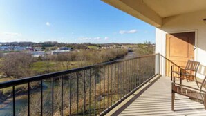 A balcony with a view of a river and distant buildings.