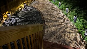 A wooden deck with a gravel path leading to a grassy area, surrounded by a wooden fence.