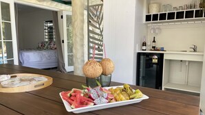 Uma mesa de jantar de madeira com um prato de frutas, dois cocos com canudos e uma bandeja decorativa.
