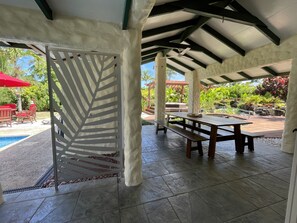 An outdoor patio area with a pool, covered seating, and a wooden table. - Villa Honohitu w/pool, bbq outdoor space, and mini bar (Takitumu District)