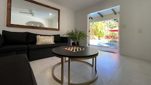 Uma sala de estar com um sofá preto, uma mesa de centro redonda e um espelho grande na parede.