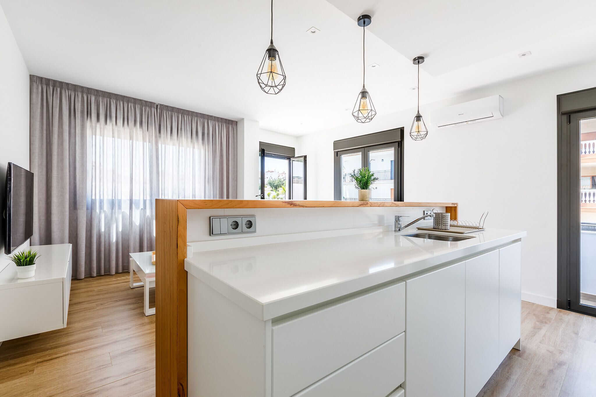 A modern kitchen with a central island, pendant lighting, and a view to the outside.