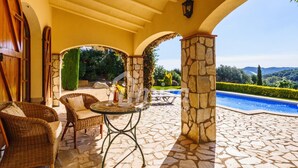 A patio with wicker furniture, a stone pillar, and a pool. - Villa Isabela, Calonge - Costa Brava (Calonge)