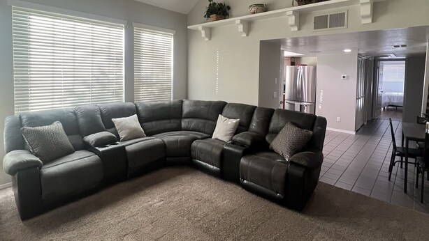 A living room with a sectional sofa, ceiling fan, and a kitchen area in the background. - Scottsdale Couples Getaway| Pool & Hot Tub| Scenic (Scottsdale)