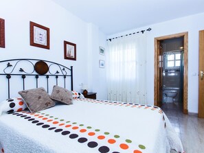 Cozy retreat with a neatly made bed, wooden headboard, and a bedside table with a lamp.