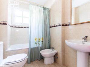 Bathroom features a shower, toilet, bidet, and sink with a mirror above.