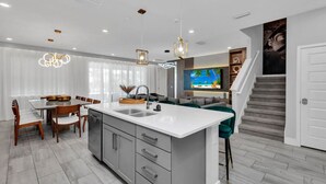 Une cuisine moderne dotée d’un îlot central, d’un coin repas avec des chaises et d’un escalier menant à un autre niveau.