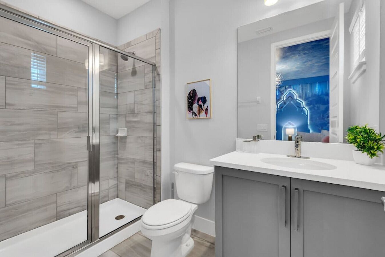 A modern bathroom with a glass-enclosed shower, a white toilet, and a vanity with a mirror.