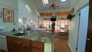 Una cocina amplia con una isla grande, un comedor con mesa y sillas, y vistas al exterior a través de amplios ventanales.