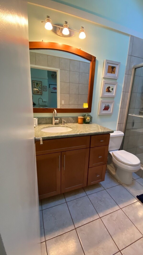 Un baño con tocador, lavabo, espejo y retrete.