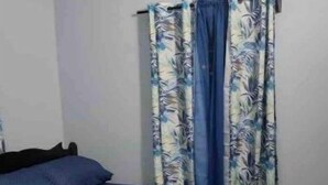 A bedroom with a bed, a window with curtains, and an air conditioning unit. - 2 BR w/ AC APT near Grand Anse Beach -15 mins walk, 10 mins away from airport. (The Lime)