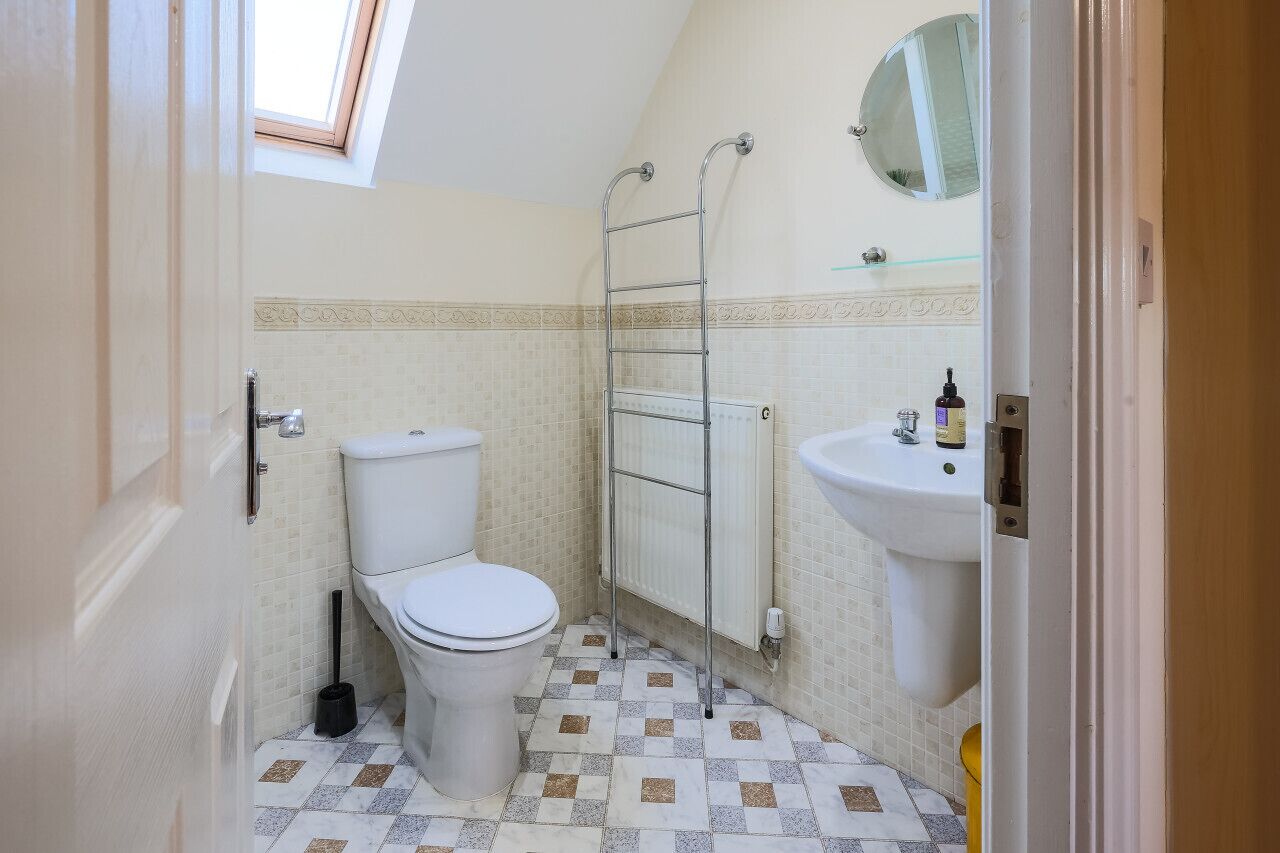 Une petite salle de bain comprenant des toilettes, un radiateur, un lavabo et un miroir.