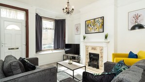 Una sala de estar con chimenea, televisor y un sillón amarillo.