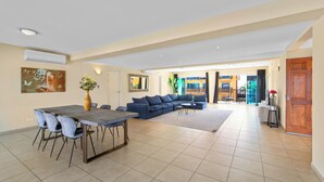 A spacious living area with a dining table, blue sofa, and a large window.