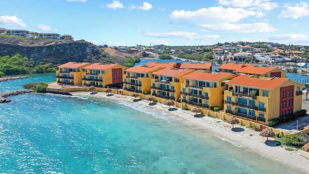 A coastal hotel with multiple balconies, a beachside location, and a view of the surrounding landscape.