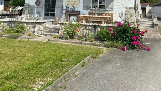 Un edificio de dos pisos con fachada de piedra, un balcón y un cartel que dice "Dorftherm".