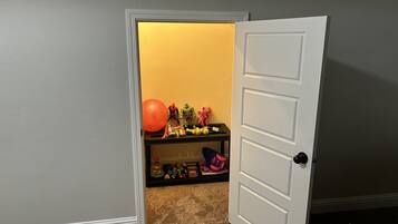 A room with a door leading to a storage area containing toys and a ball.