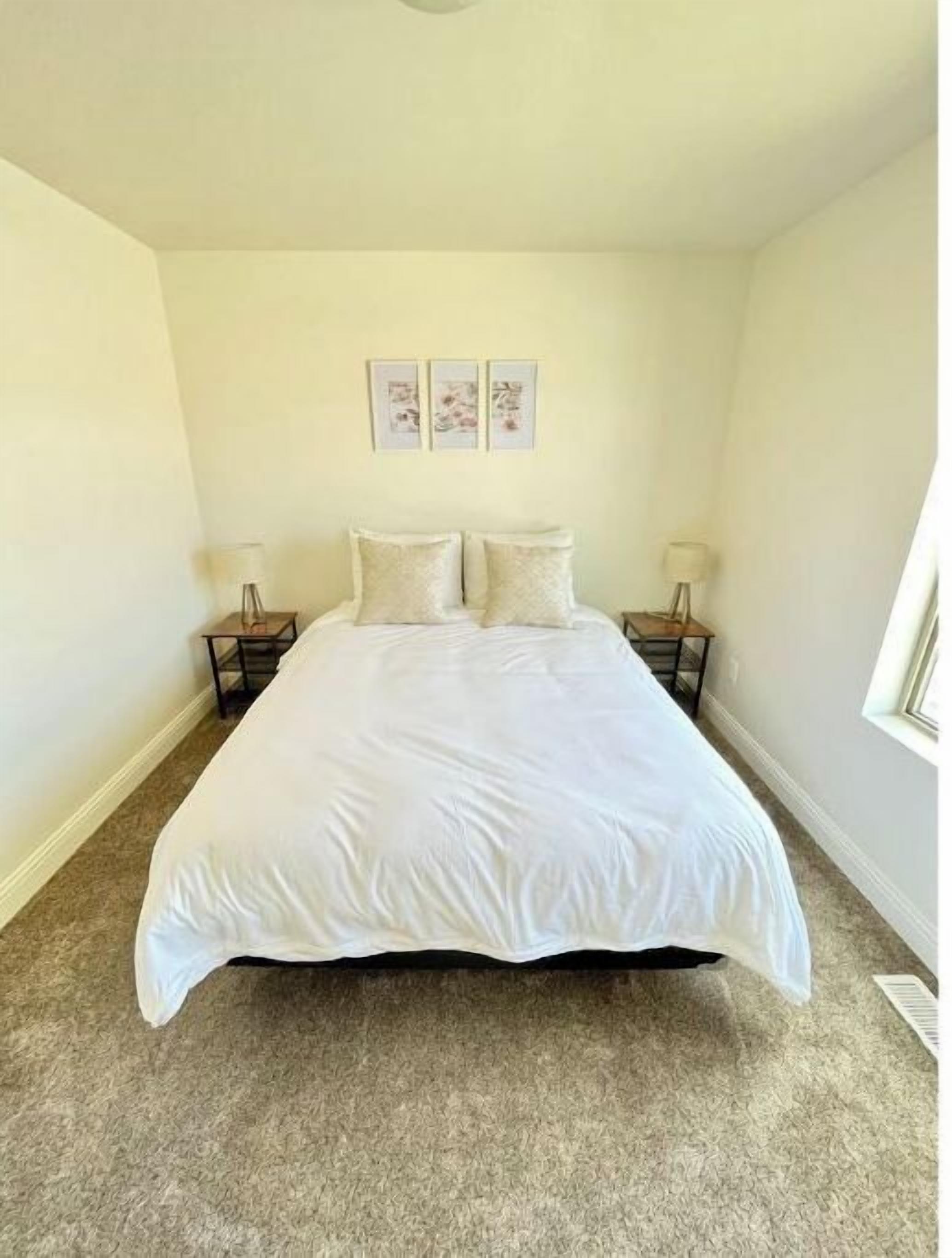 A bedroom with a large bed, two bedside tables, and a window.