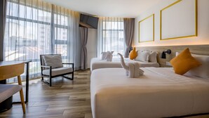 Habitación de hotel con dos camas, una silla, una mesa y un televisor.
