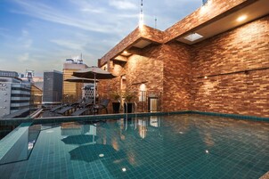 Una piscina al aire libre, sombrillas, sillones reclinables de piscina
