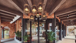Vestíbulo de hotel con fachada de ladrillo, amplias puertas de cristal y múltiples lámparas colgantes.