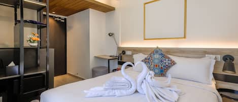 A hotel room with a bed, a wardrobe, a bedside table with a lamp, and a wall-mounted picture frame.