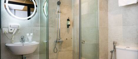 A modern bathroom with a glass-enclosed shower, a sink with a mirror, and a toilet.