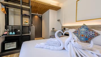 Habitación de hotel con cama, armario, microondas, cafetera y almohadón decorativo.