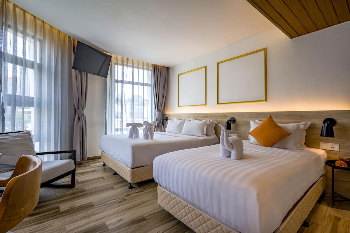 A hotel room with two beds, a TV, and a desk with a chair.