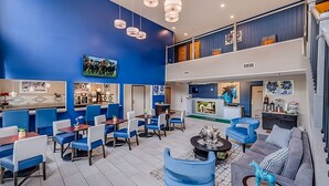A spacious lobby with a blue and white color scheme, featuring a seating area with blue chairs and tables, a grey sofa, and a staircase leading to an upper level. - Relaxing Unit Near Attractions in GuestHouse Lexington, Parking! (Lexington)