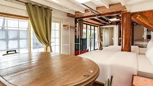 A cozy room with a round wooden table, a white sofa, and a large window with curtains. - WOO MI GWAN HOTEL (Seoul)