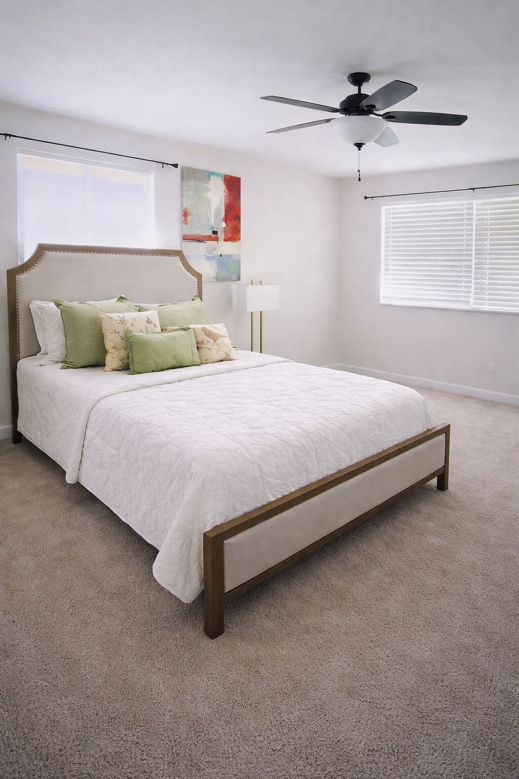 Quarto com cama, ventoinha no teto, janela com persianas e um quadro na parede.