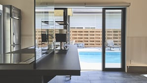 Una cocina moderna con horno integrado y un amplio ventanal con vistas a una zona de piscina.