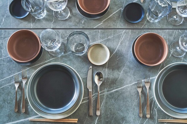 A table set with plates, bowls, glasses, cutlery, and chopsticks on a marble surface. - VILLA SAISON FUJI (Fujikawaguchiko)