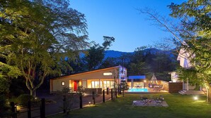Una casa moderna con piscina, terraza techada y césped cuidado.