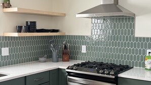 A kitchen with green hexagonal tiles, a gas stove, and a stainless steel range hood. - Lovely cottage with fenced in back yard (Wausau)