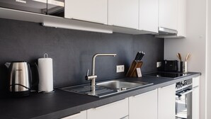 Een moderne keuken met een zwart aanrecht, roestvrijstalen apparatuur en witte keukenkastjes.