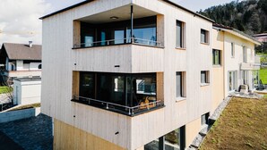 Een modern meerlaags gebouw met balkons, grote ramen en een plat dak.
