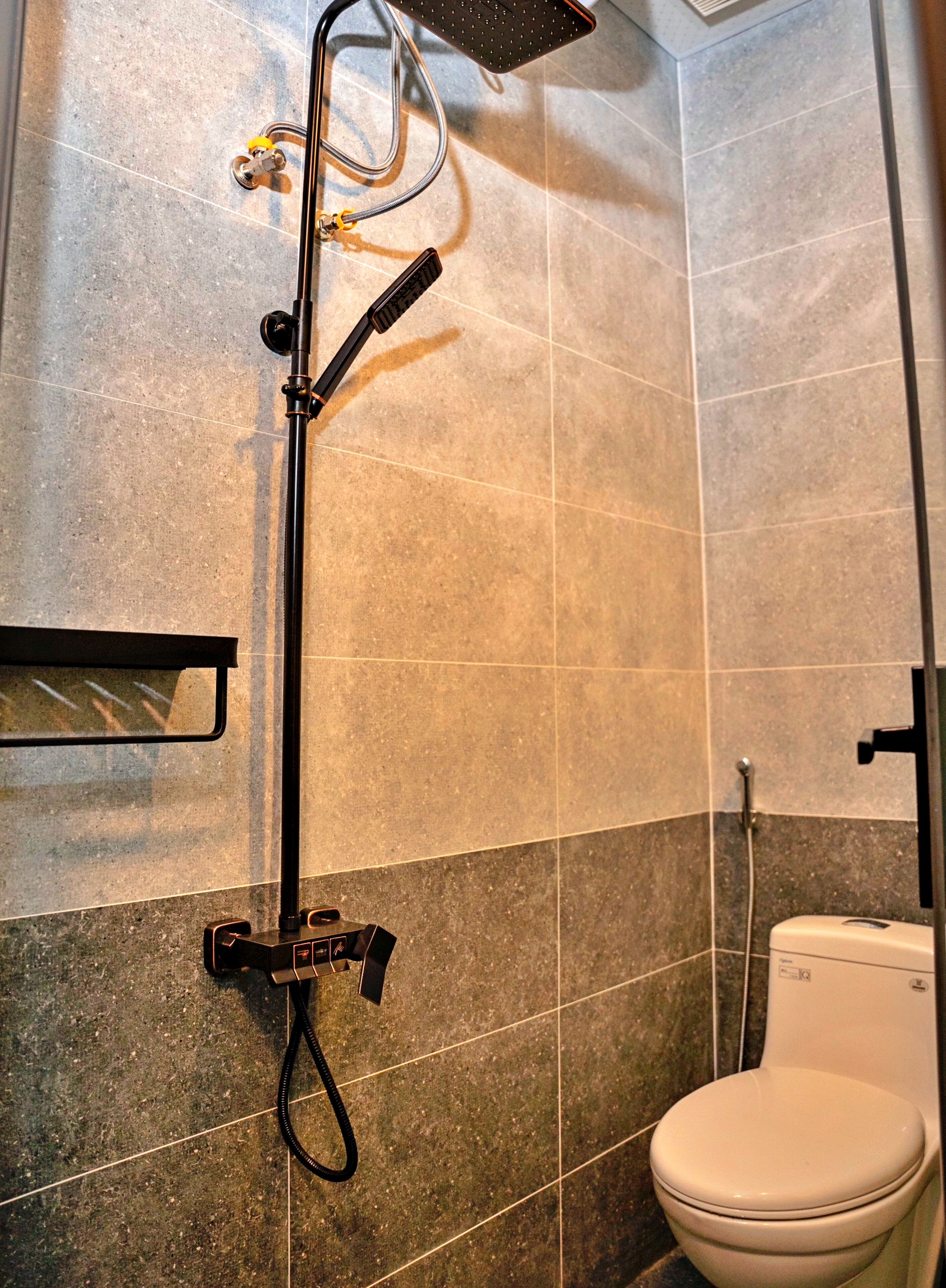 A bathroom with a shower, toilet, and a towel rack.