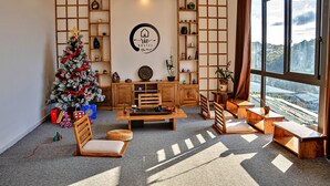 Una habitación acogedora con un árbol de Navidad, muebles de madera, una estantería y un ventanal con vistas a la ciudad.