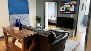 Una sala de estar con una mesa de centro de madera, un sofá de cuero negro, un televisor y una chimenea.