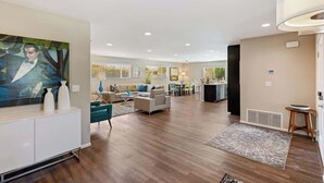 A spacious living area with a large painting, a sofa set, and a dining area. - Sunrise Superstar: Awesome Backyard, Huge Fire Pit (Palm Springs)