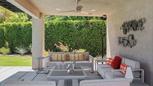 An outdoor patio with a ceiling fan, a sofa set, and a dining table. - Sunrise Superstar: Awesome Backyard, Huge Fire Pit (Palm Springs)