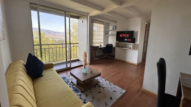 Un salon moderne avec un canapé, une table basse et un téléviseur fixé au mur.